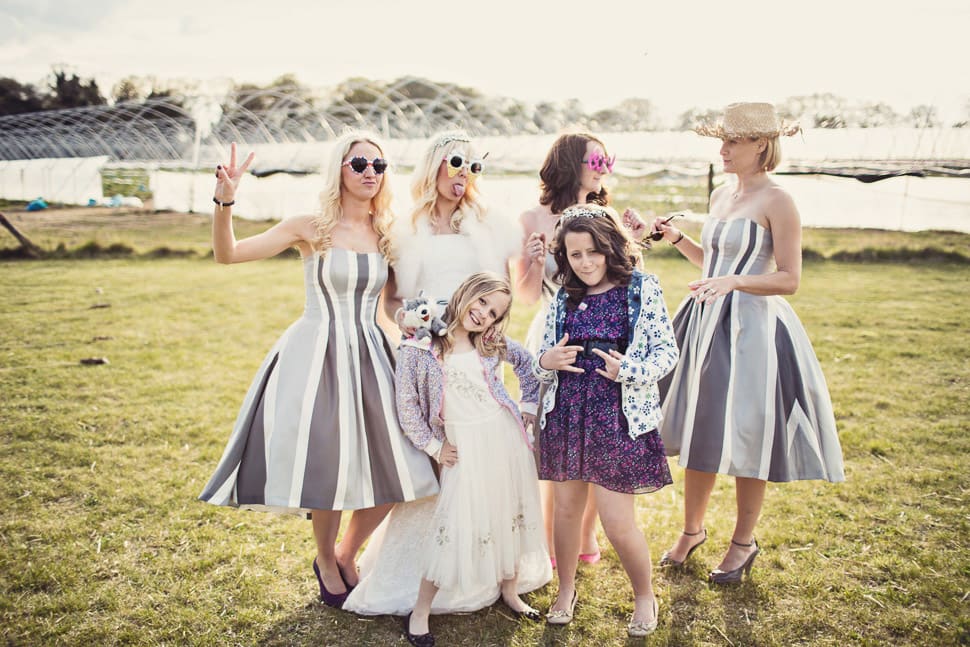 Bridebook.co.uk- bride bridesmaids and flower girl posing with props