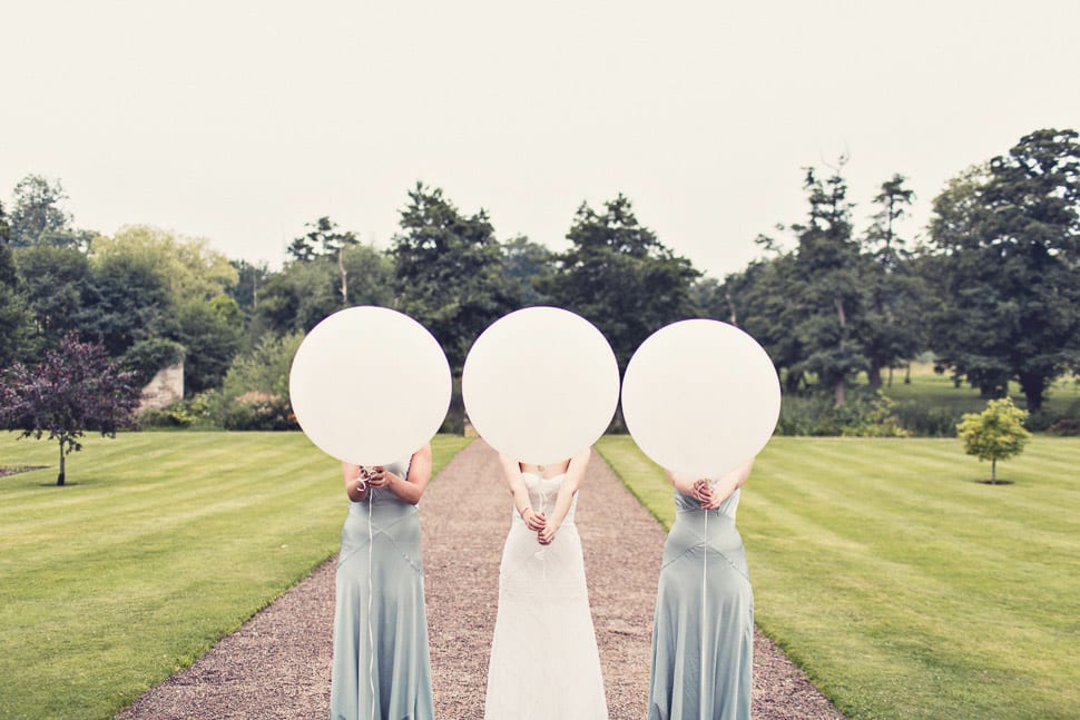 Bridebook.co.uk- bride and bridesmaids holding big white baloons