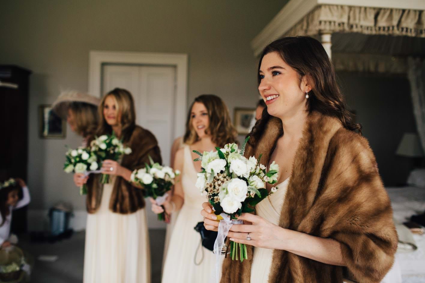 Bridebook.co.uk- bridesmaids in matching dresses and faux fur covers