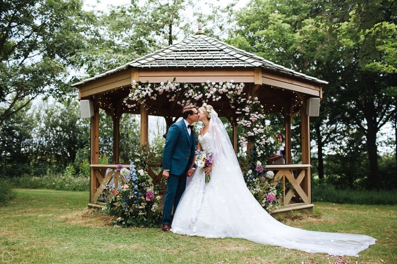 newlyweds kiss in front a gazeebo at crockwell farm