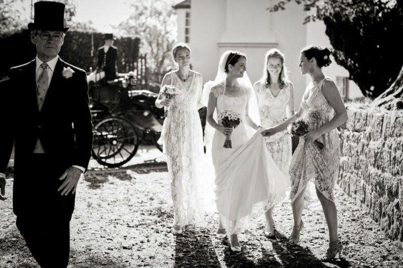 Bridebook.co.uk- bride and bridesmaids walking away from horse carriage