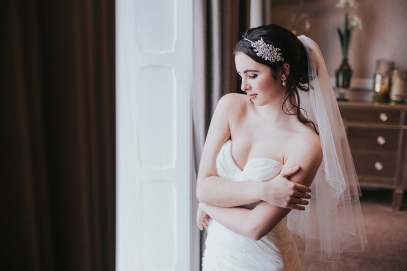 a bride with an updo wears a diamante headband and veil 