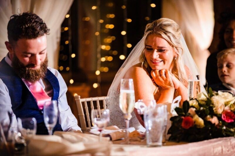 a bride and a groom smiling at the top table drinking champagne 