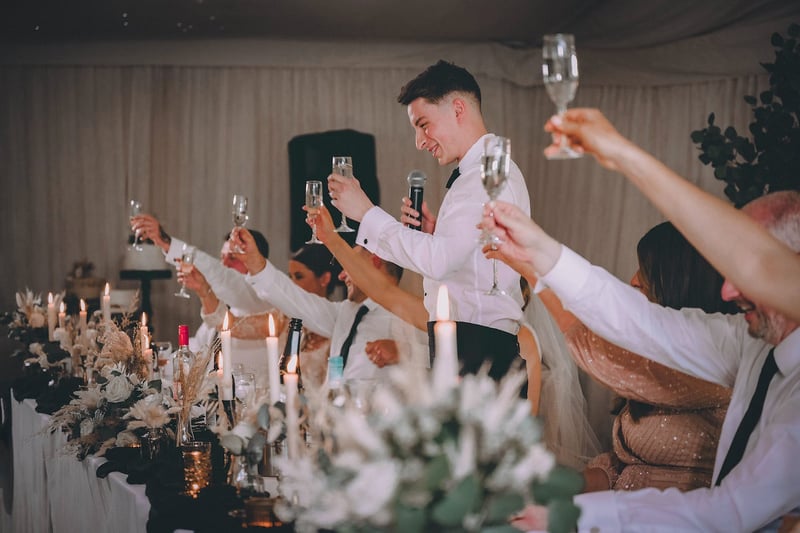 the best man raising a glass to the newly wedded couple