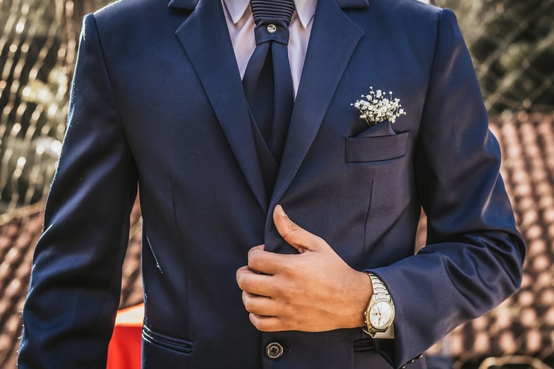 Gros plan sur une boutonnière florale épinglée sur un costume, mettant en valeur un détail subtil mais essentiel du look du marié.