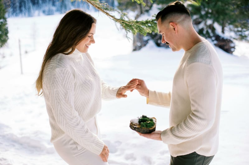 Couple en train d'échanger des alliances dans un paysage enneigé