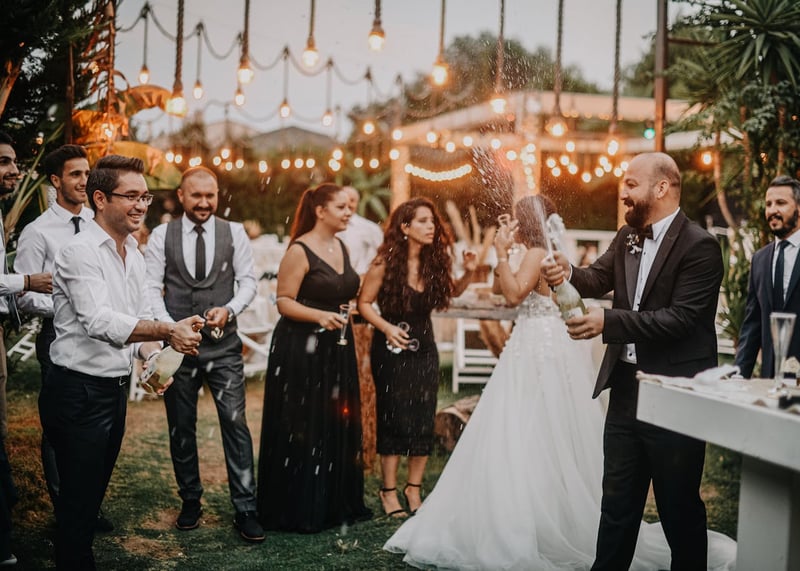Des invités bien habillés célèbrent avec des coupes de champagne tandis qu’un homme ouvre une bouteille avec éclat, entouré de guirlandes lumineuses et d’une ambiance chaleureuse.