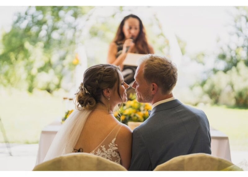 Rednerin spricht Glückwünsche zur Hochzeit, Brautpaar blickt sich verliebt an