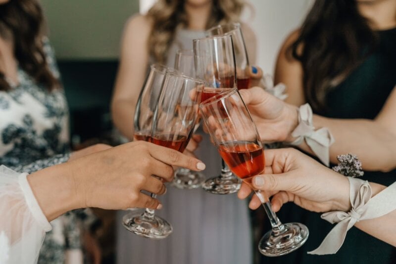 Detailaufnahme von Roséwein-Gläsern beim Anstoßen auf Glückwünsche zur Hochzeit