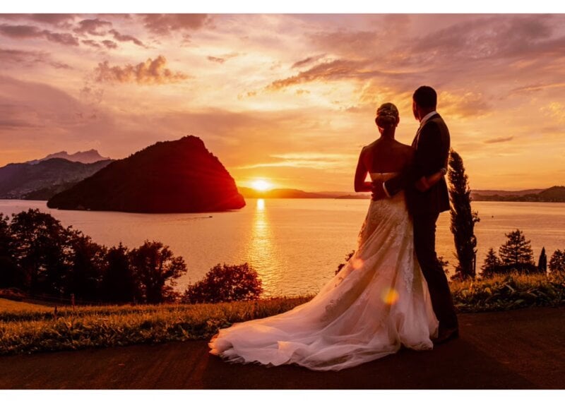 Brautpaar genießt den Sonnenuntergang mit Blick auf den See als Silhouette vor traumhafter Kulisse