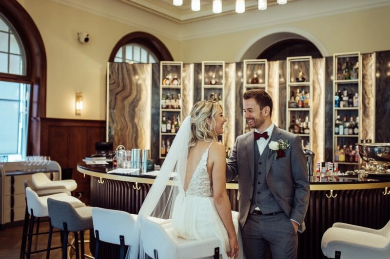Brautpaar lächelt sich an eleganter Hotelbar während der Hochzeitsfeier zu