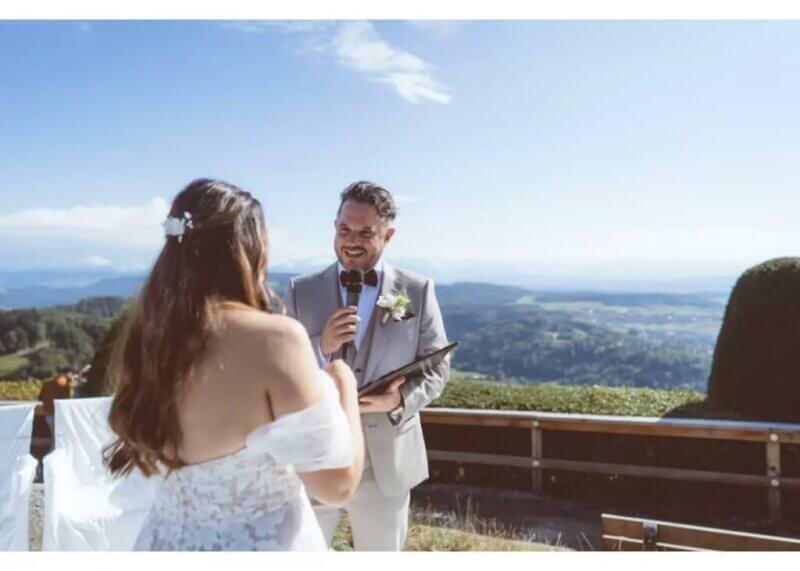Bräutigam spricht Hochzeitswünsche am Mikrofon vor beeindruckendem Bergpanorama