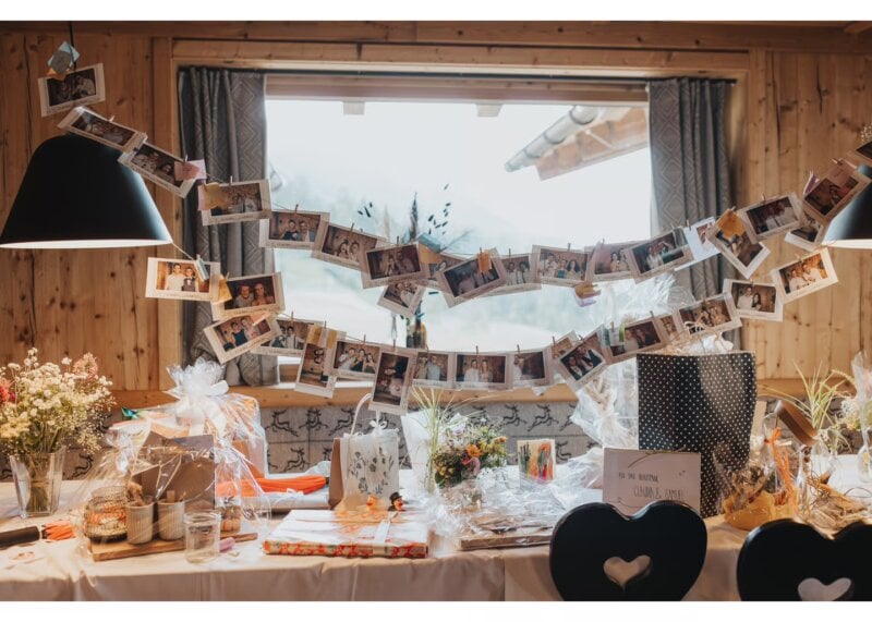 Girlande aus Fotoabzügen hängt über einem Tisch mit liebevoll verpackten Hochzeitsgeschenken