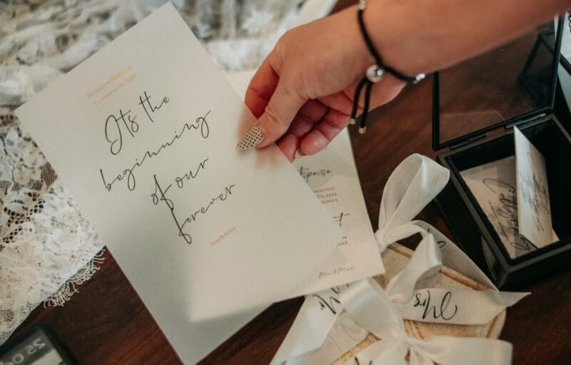 Hand hält kalligrafierte Hochzeitskarte mit herzlichem Spruch fürs Gästebuch