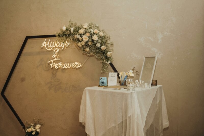 Gästebuchtisch mit Neonschriftzug „Always & Forever" und Blumendekoration