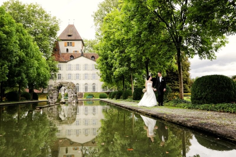 Brautpaar geht Hand in Hand am Spiegelteich im Schlosspark entlang