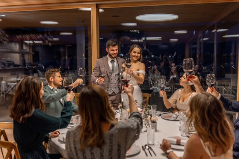 Brautpaar nimmt abends emotionale Glückwünsche zur Hochzeit entgegen, Gäste heben Gläser