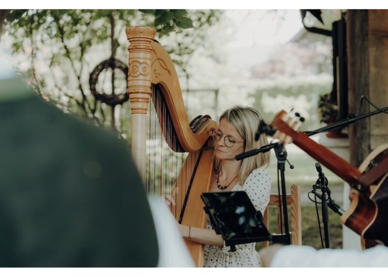 Harfenistin spielt bei der Trauung im Freien vor grüner Kulisse