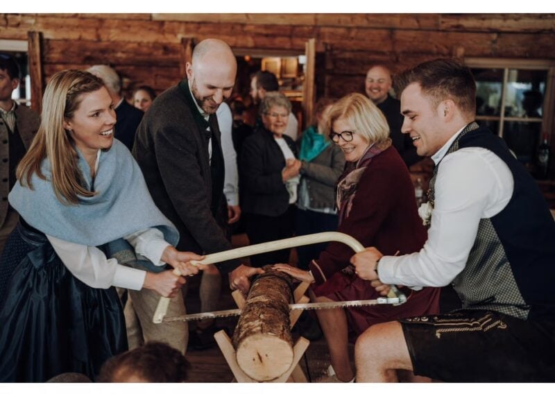 Brautpaar sägt traditionell einen Baumstamm durch beim Hochzeitsbrauch