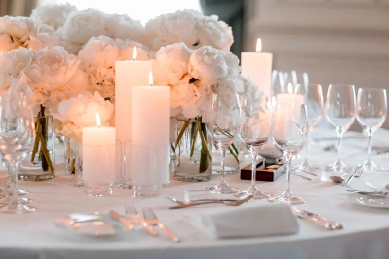 Festlich gedeckter Hochzeitstisch mit weißen Blumen und brennenden Kerzen