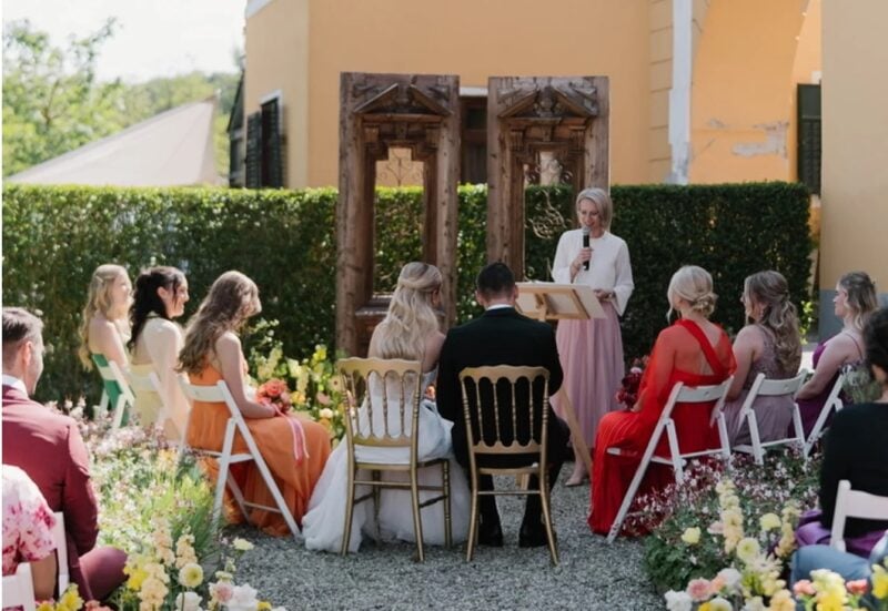 Freie Trauung im Garten mit Gästen in orangefarbenen, roten und weinroten Hochzeitsfarben