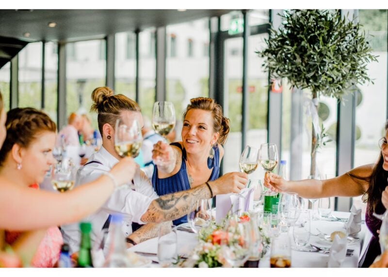 Gäste stoßen fröhlich mit Weingläsern an einer festlich gedeckten Tafel an