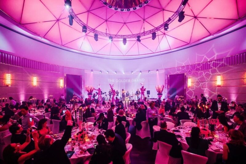 Live-Band performt auf Bühne bei Hochzeitsfeier in pink beleuchtetem Ballsaal mit Gästen