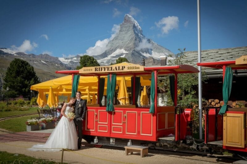 Brautpaar steht vor einer historischen Bergbahn mit Blick auf das Matterhorn