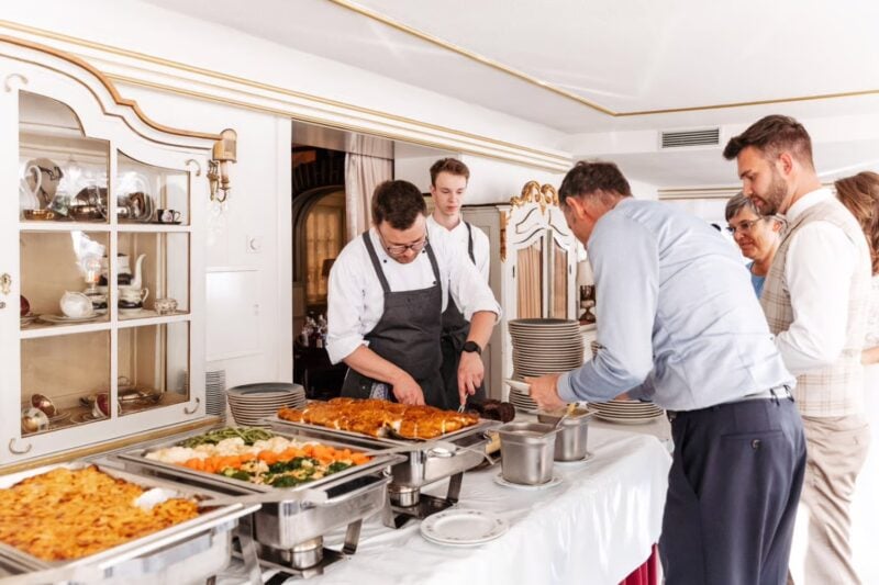 Gäste bedienen sich am Hochzeitsbuffet mit warmen Speisen