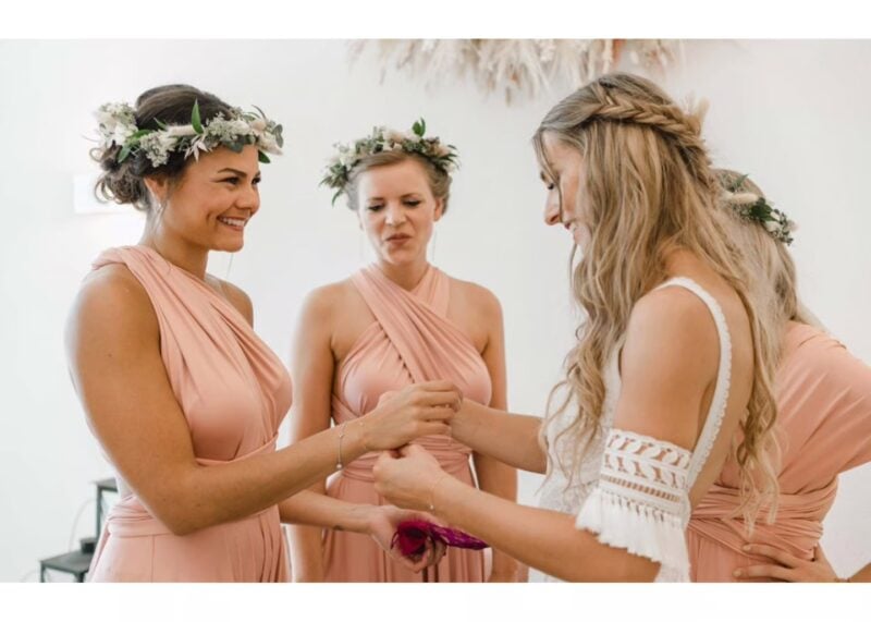 Braut mit blumenbekränzten Trauzeuginnen in zarten Roben vor der Zeremonie