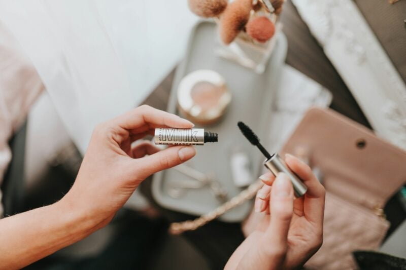 Braut hält Mascara und Applikator für ihr Braut-Make-up bereit