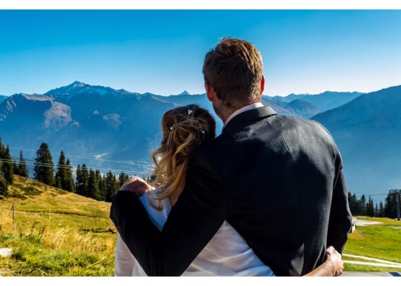 Brautpaar steht Arm in Arm und blickt auf das Alpenpanorama beim Madrisa-Hof