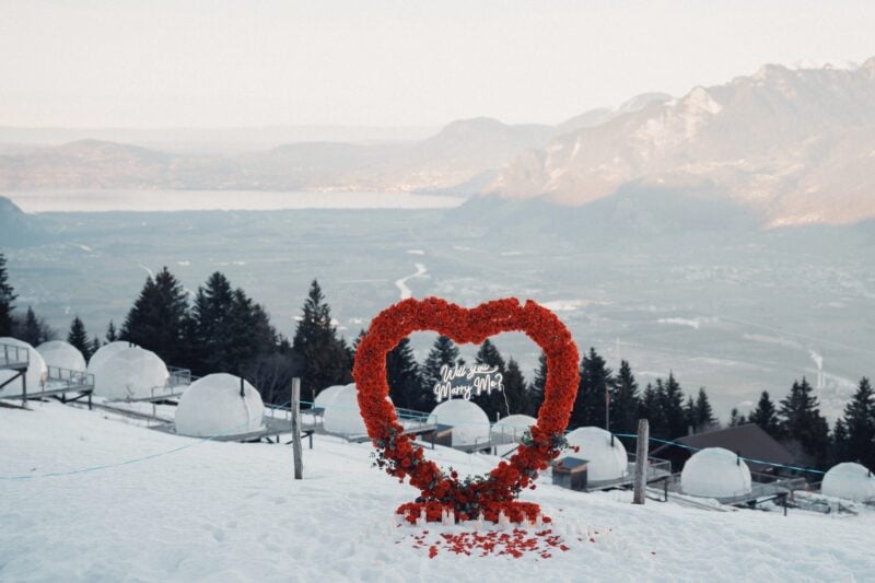 Rotes Blumenherz vor Iglu-Zelten im Schnee mit Alpenpanorama – romantischer Ort im Whitepod Original