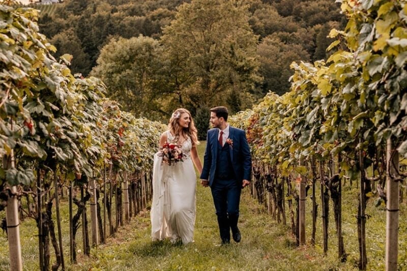 Brautpaar spaziert Hand in Hand durch die Weinreben des Weinschloss Thaller