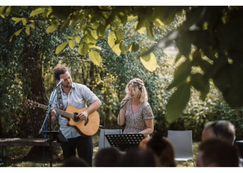 Live-Band mit Gitarre und Gesang unterhält die Hochzeitsgäste im Freien – Beispiel für gelungene Hochzeitsunterhaltung