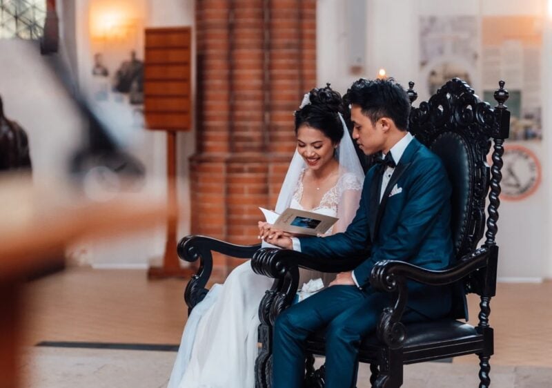 Brautpaar liest gemeinsam lächelnd eine Fürbitte zur Hochzeit während der kirchlichen Trauung