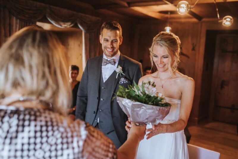 Brautpaar freut sich über Blumenstrauss von einer Gästin