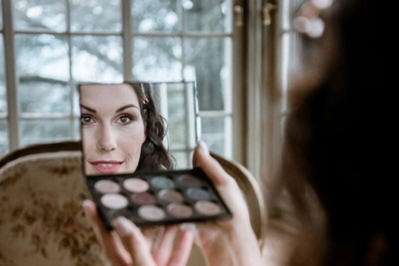 Braut prüft ihr Lidschatten-Make-up im Handspiegel im St. Charles Hall