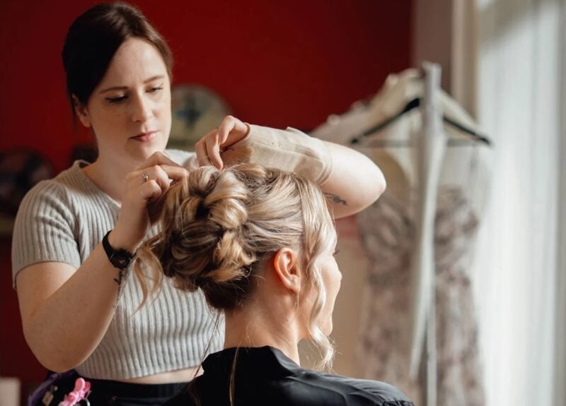 Stylistin steckt die Haare der Braut im bloomeventhaus zu einem eleganten Dutt hoch
