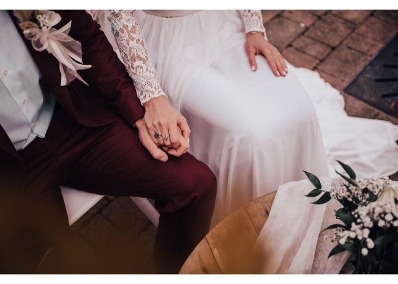 Nahaufnahme von Brautpaar-Händen mit Brautstrauß beim Hochzeitsempfang im Weinhof & Feiergut F. Kohl
