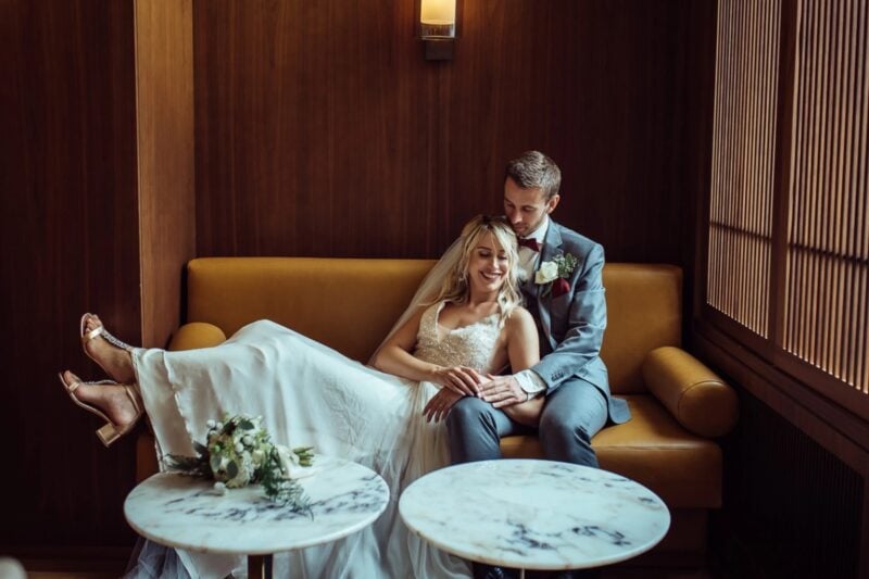Brautpaar entspannt auf einem Samtsofa in der Lounge des Kempinski Palace Engelberg
