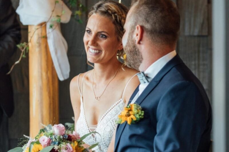Lächelnde Braut mit buntem Blumenstrauss neben dem Bräutigam – Hochzeit im HUUS Gstaad