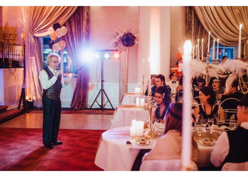 Zauberkünstler unterhält Gäste bei elegant dekorierter Gala-Hochzeit im Great-Gatsby-Stil – passende Unterhaltungsidee je nach Hochzeitsstil