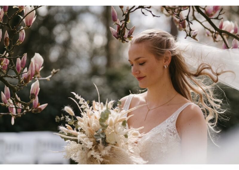 Braut mit Trockenblumenstrauß unter blühendem Magnolienbaum – Inspiration für romantische Hochzeitssprüche im Boho-Stil
