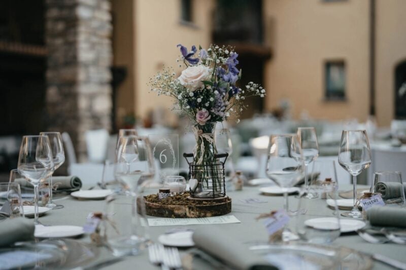 Hochzeitstisch mit Tischnummer, Wildblumen-Gesteck und Namenskärtchen auf jedem Platz in der Masseria la Tana