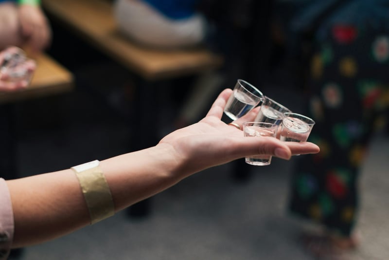 outstretched hand holding three clear shot glasses for hen do games