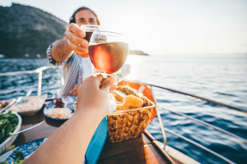 Couple drinking wine on the yacht at  sunset. Toasting on a yacht.