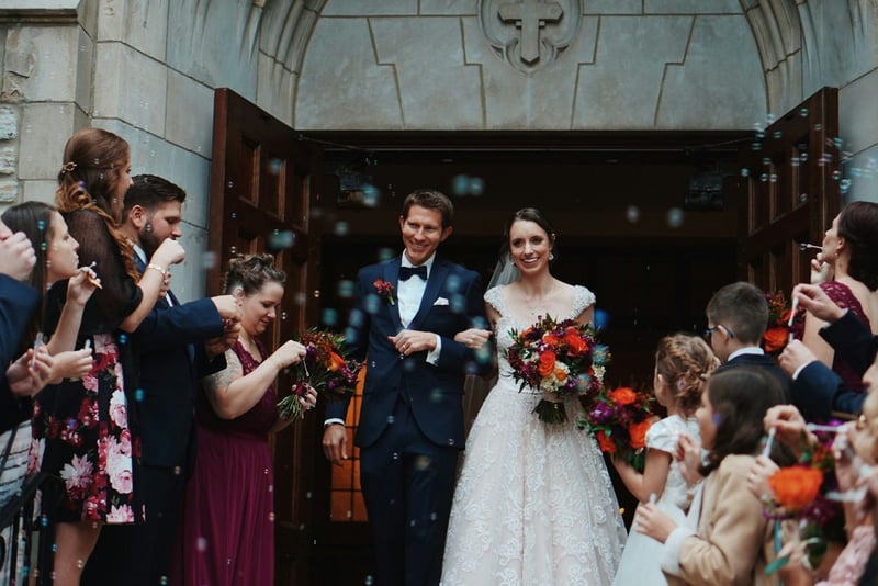 A bride and groom being scattered with confetti as they leave their wedding ceremony