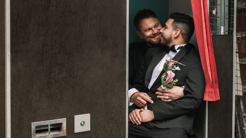two grooms smiling in a retro photobooth together