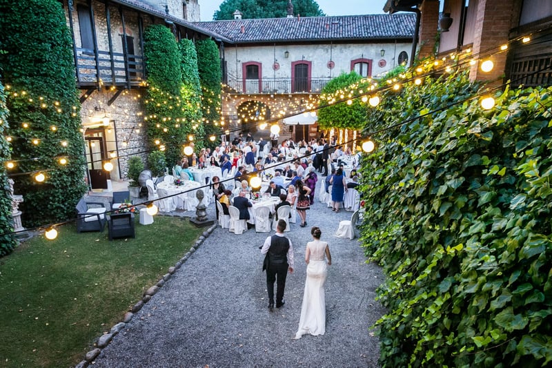 A bride and groom approach an outdoor wedding reception hand in hand